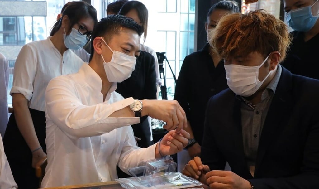 Danny Yeung (left), CEO of Prenetics, hands out coronavirus testing kits to restaurant groups in Hong Kong’s Central. Photo: SCMP/K.Y. Cheng