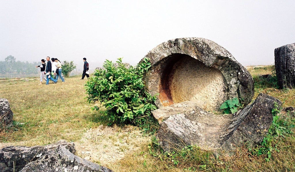 Tourists walk past the remains of a prehistoric stone jar believed to have been broken during US aerial bombing at Site 1 at the Plain of Jars. Photo: AFP