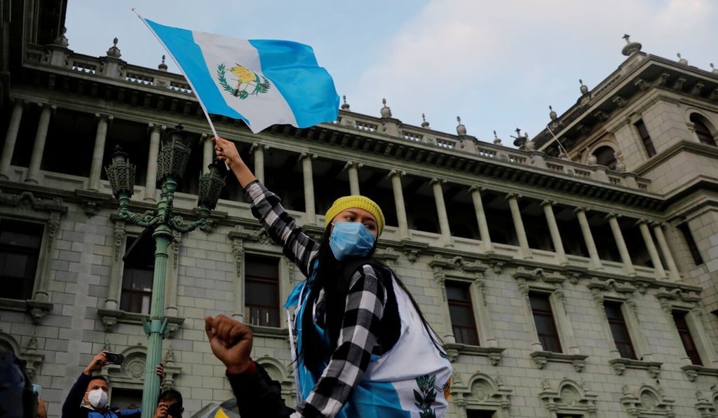 A woman holds up a Guatemalan flag on Sunday during a protest to demand the resignation of President Alejandro Giammattei. Photo: Reuters A woman holds up a Guatemalan flag on Sunday during a protest to demand the resignation of President Alejandro Giammattei. Photo: Reuters