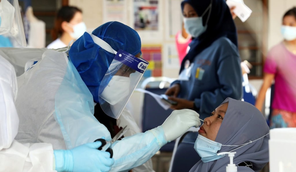 A medical worker collects a swab sample from a Top Glove worker to be tested for Covid-19. Photo: Reuters A medical worker collects a swab sample from a Top Glove worker to be tested for Covid-19. Photo: Reuters