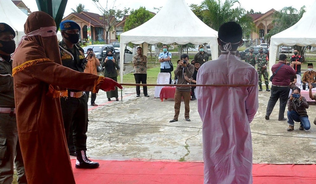 A sharia officer whips the offender in Idi Rayeuk, East Aceh on November 26, 2020. Photo: AFP