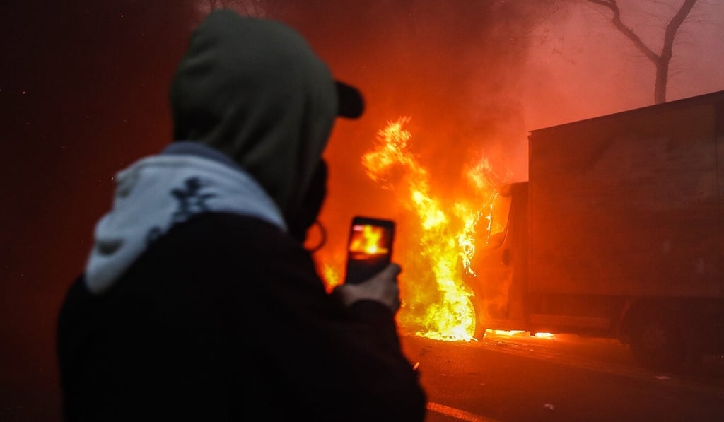 A man records on his phone a car burning during a protest in Paris on Saturday. Photo: EPA