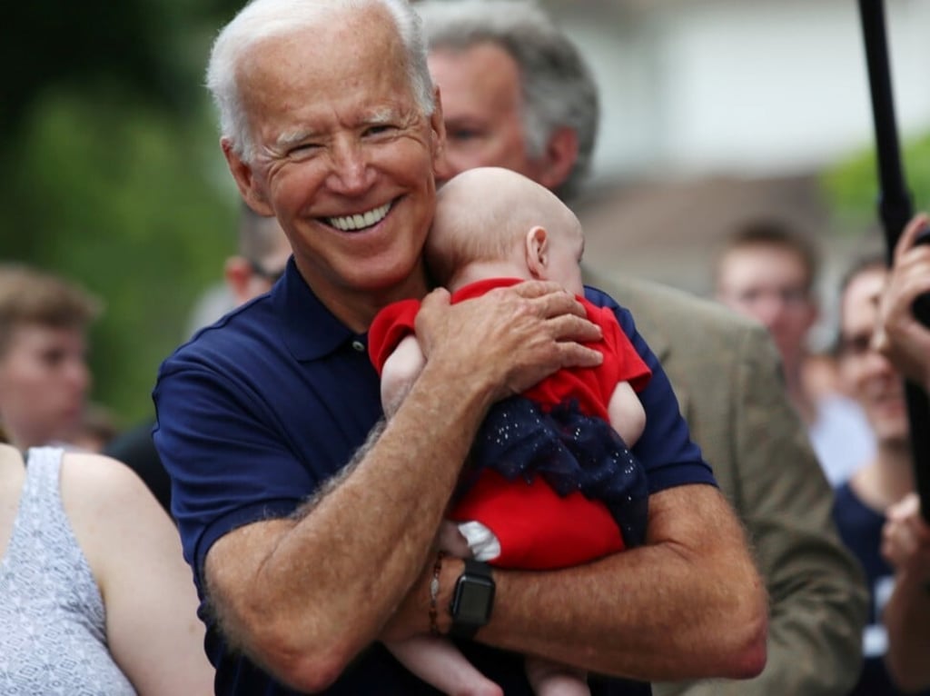 Joe Biden holds a baby at an Independence Day parade in Iowa last year, and flashes his Apple Watch to the cameras. Photo: Reuters