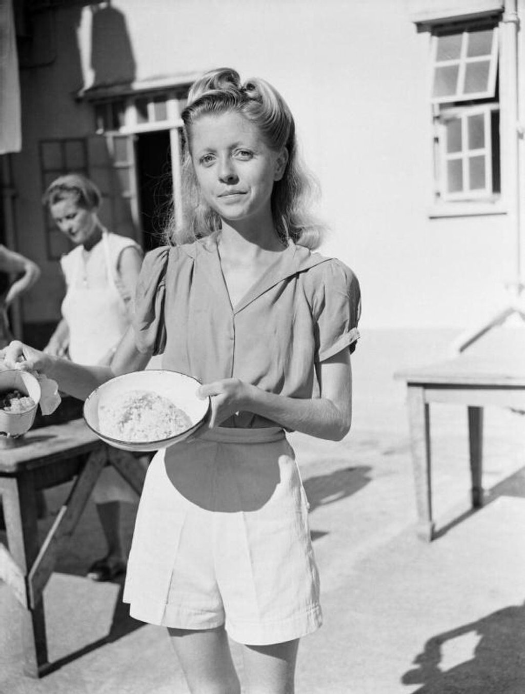 Internee Wendy Rossini shows the portion of rice and stew that served as rations for five people. Photo: Imperial War Museum