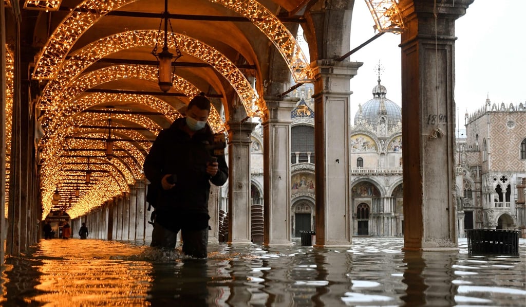 A man walks across an arcade by a flooded St Mark's Square in Venice on Tuesday. Photo: AFP A man walks across an arcade by a flooded St Mark's Square in Venice on Tuesday. Photo: AFP