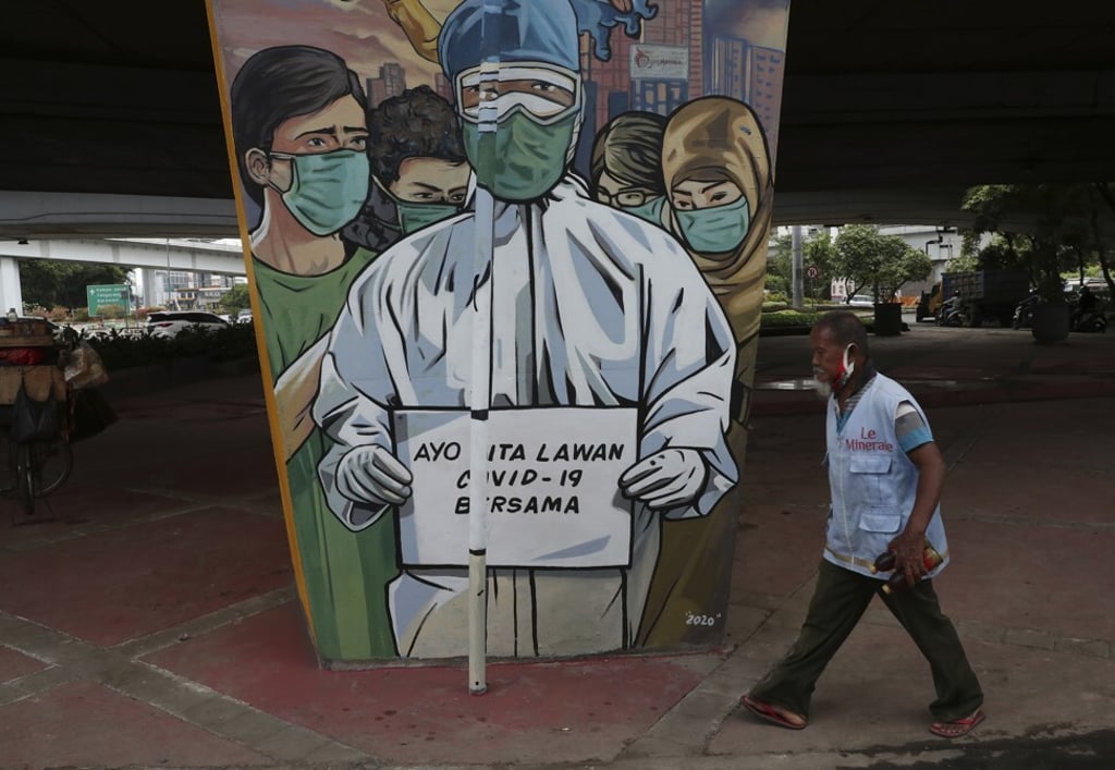 A man walks past a coronavirus-themed mural in Jakarta. Photo: AP
