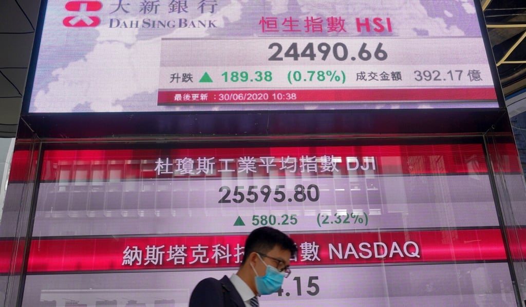 A man walks past an electronic board showing the Hong Kong stock index on June 30. Photo: AP