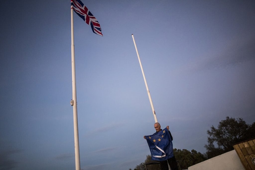 A worker folds the EU flag after being lowered in Gibraltar, a British colony off Spain’s southern tip, on January 31. The EU-UK deal does not cover Gibraltar, and Madrid and London are still negotiating how their shared border will be transformed once the Brexit transition period ends on December 31. Photo: AP A worker folds the EU flag after being lowered in Gibraltar, a British colony off Spain’s southern tip, on January 31. The EU-UK deal does not cover Gibraltar, and Madrid and London are still negotiating how their shared border will be transformed once the Brexit transition period ends on December 31. Photo: AP