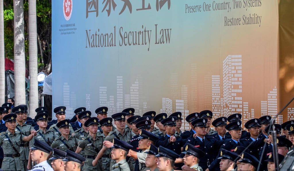 Uniform groups march past a banner of the newly imposed national security law. Photo: AFP Uniform groups march past a banner of the newly imposed national security law. Photo: AFP