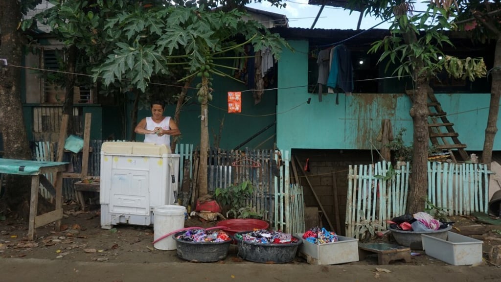 Corazon Tocio washes her family’s flood-stained clothes in front of her home in Barangay Malanday, Marikina, in Metro Manila, the Philippines. Photo: AJ Bolando