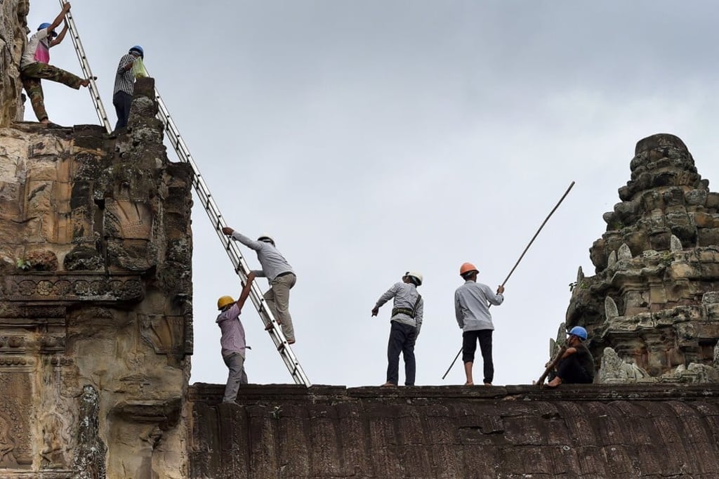 Gardeners climb a temple at Angkor Wat, to remove foliage before it damages the ancient facade, on October 12, 2020. Photo: AFP Gardeners climb a temple at Angkor Wat, to remove foliage before it damages the ancient facade, on October 12, 2020. Photo: AFP