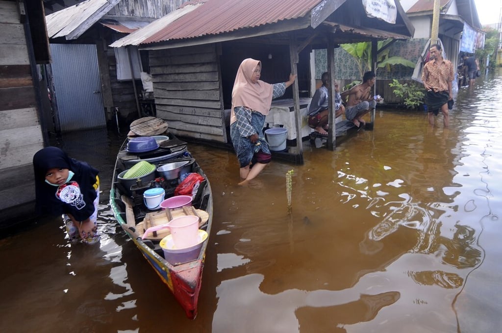 People talk outside their homes at a neighbourhood affected by floods in Banjarmasin. Photo: AP