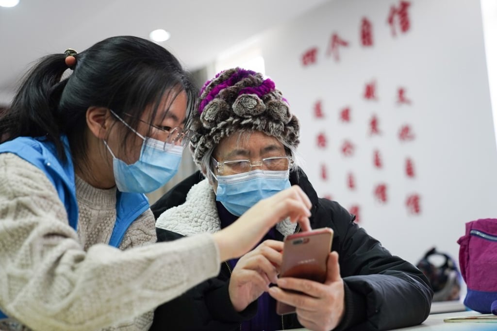 Shi Jiayi, a student volunteer from Beijing Foreign Studies University, teaches as a senior resident how to use a health-tracking app, introduced amid the COVID-19 outbreak, at a community activity centre in Haidian district in Beijing on December 8, 2020. Photo: Xinhua