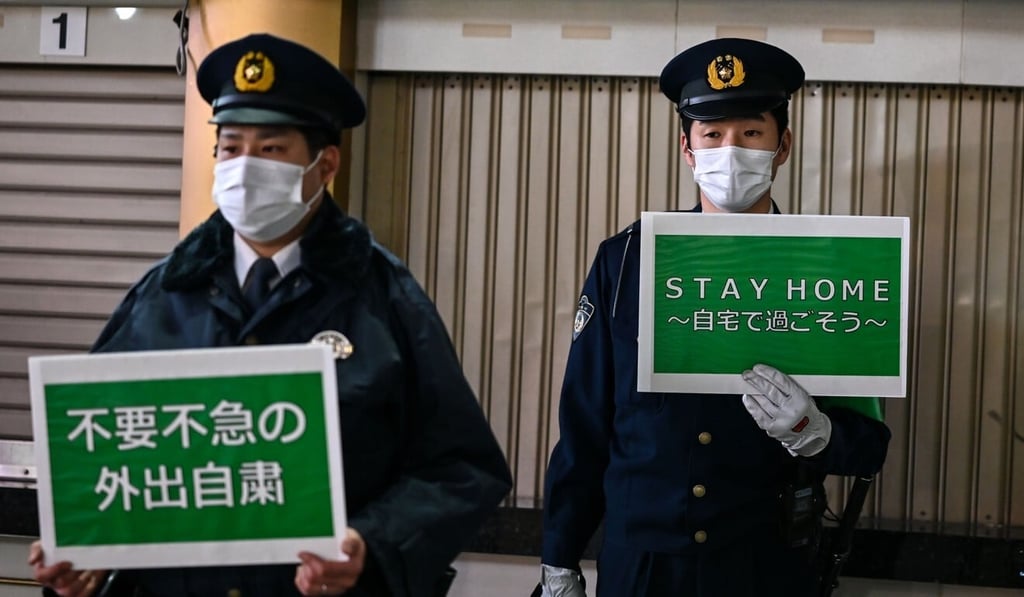 Policemen hold signs asking people to stay home amid rising coronavirus cases in Tokyo on Friday. Photo: AFP