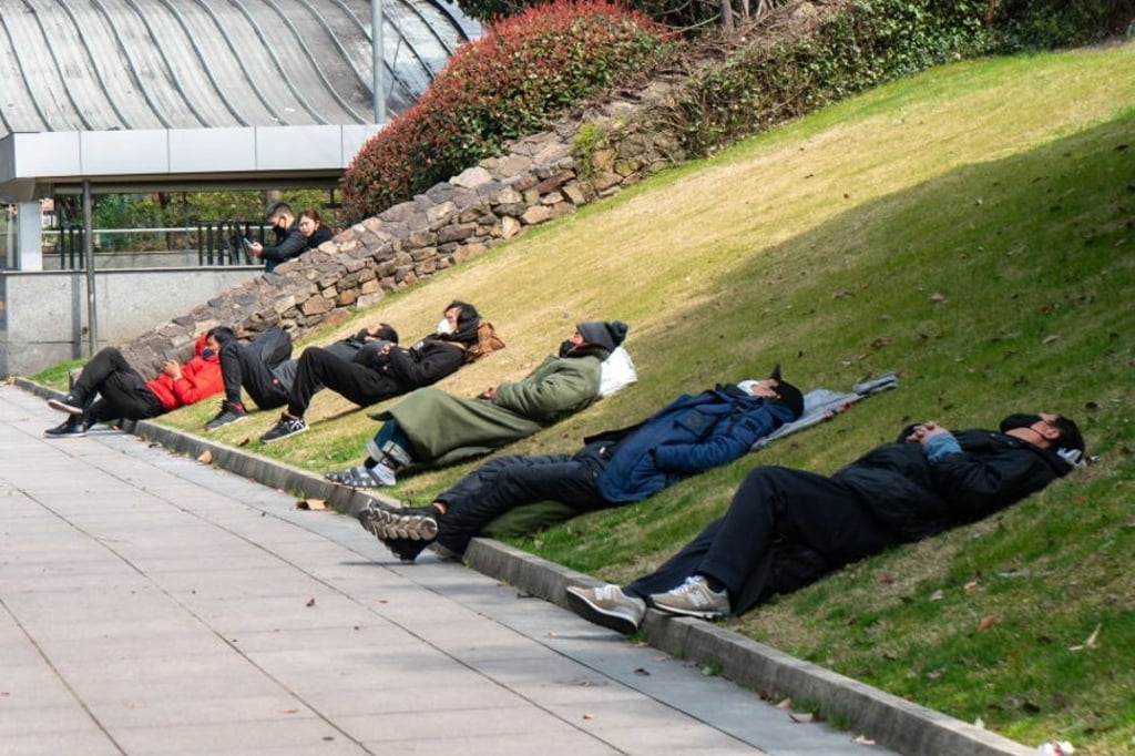 People lie down for a nap on a grassy slope near the People’s Square in Shanghai, China. Photo: Costfoto/Barcroft Media via Getty Images