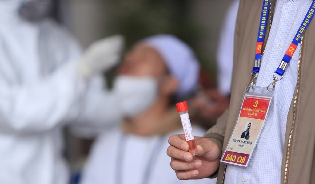 A member of the press holds a tube containing a swab sample while waiting for a Covid-19 test in Hanoi. Vietnam has beaten the coronavirus to become one of the few countries to post positive growth last year. Photo: AP A member of the press holds a tube containing a swab sample while waiting for a Covid-19 test in Hanoi. Vietnam has beaten the coronavirus to become one of the few countries to post positive growth last year. Photo: AP