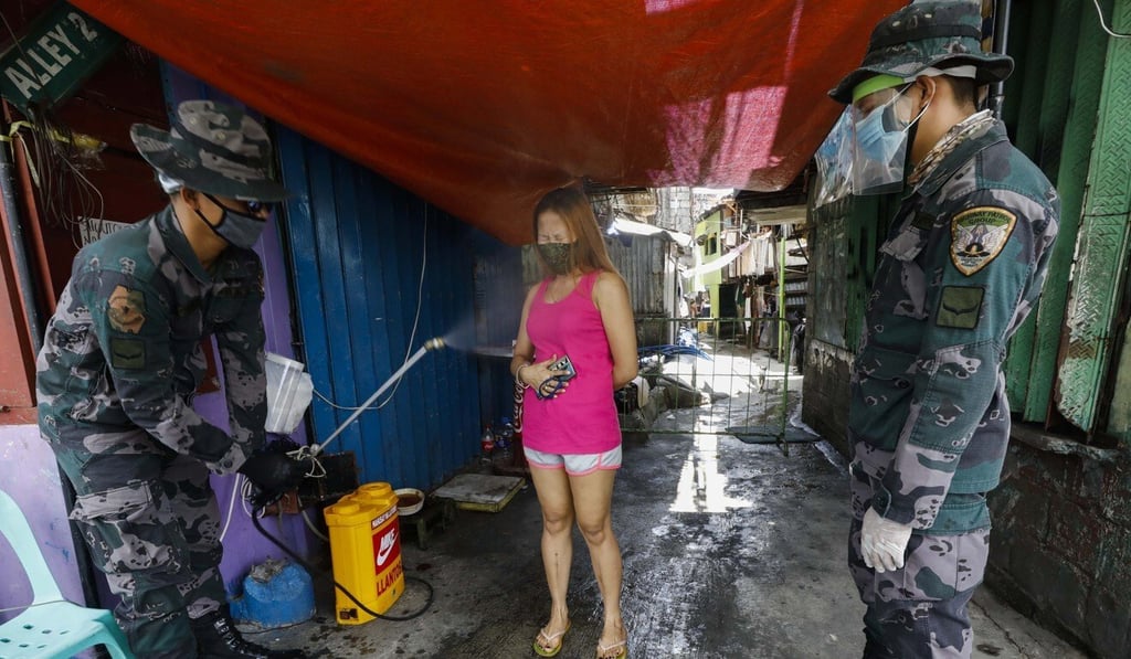 Philippine police spray disinfectant on a resident of a quarantined community in Quezon City in May last year. Photo: EPA