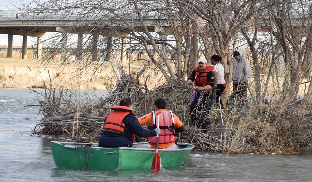 A Mexican paramedic helps a migrant family from Honduras, stranded on a tiny island while trying to cross the frigid waters of the Rio Grande river from Mexico into the US on Tuesday. Photo: Reuters