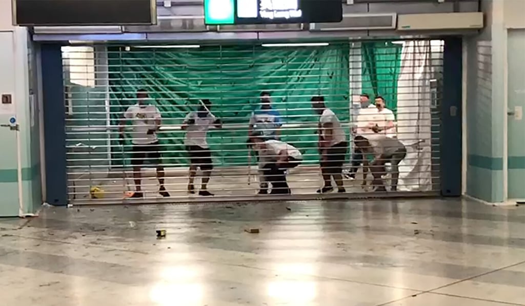 Men wearing white T-shirts attempt to pull up a locked gate at Yuen Long MTR station during the attack. Photo: SCMP Men wearing white T-shirts attempt to pull up a locked gate at Yuen Long MTR station during the attack. Photo: SCMP