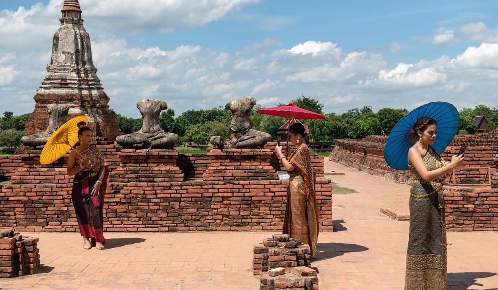 Visitors carrying sun umbrellas pose for photos at the 17th-century Wat Chaiwatthanaram temple complex in the ancient capital of Ayutthaya. Photo: AFP