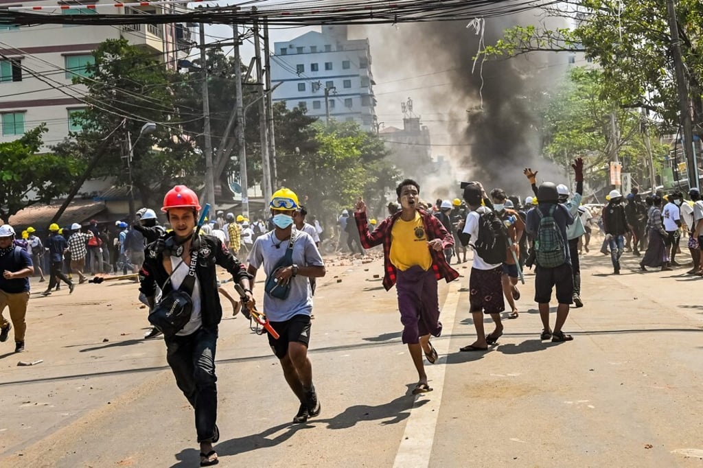 Protesters run as tear gas is fired by security forces in Yangon’s Thaketa township on March 19, 2021. Photo: AFP Protesters run as tear gas is fired by security forces in Yangon’s Thaketa township on March 19, 2021. Photo: AFP
