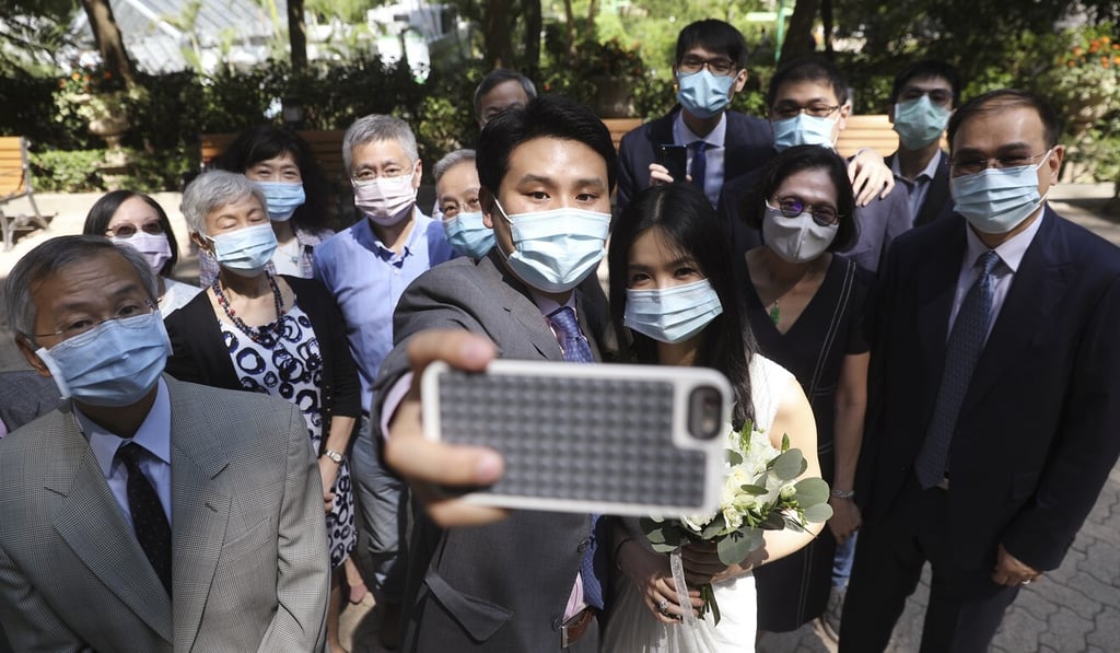 A couple take a photo outside Cotton Tree Drive Marriage Registry in Admiralty after getting their marriage registered amid the coronavirus outbreak. Photo: Winson Wong