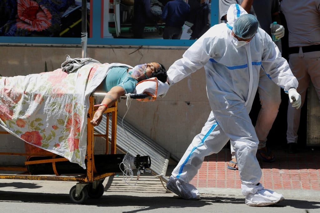 A health worker wearing personal protective equipment carries a patient suffering from Covid-19 outside the casualty ward at Guru Teg Bahadur hospital, in New Delhi, India, on April 24. Photo: Reuters