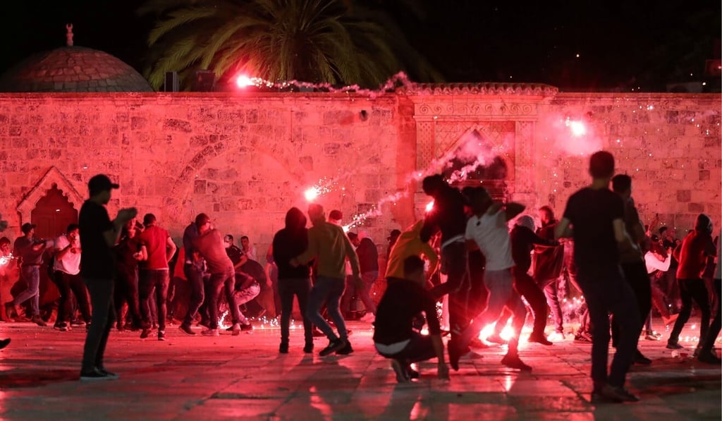 Palestinians react as Israeli police fire stun grenades during clashes at the compound that houses the Al-Aqsa Mosque in Jerusalem on Friday. Photo: Reuters Palestinians react as Israeli police fire stun grenades during clashes at the compound that houses the Al-Aqsa Mosque in Jerusalem on Friday. Photo: Reuters