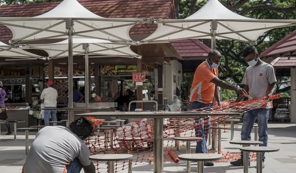 Workers place a plastic cordon around a table to restrict capacity at a food court in Singapore earlier this week. Photo: EPA
