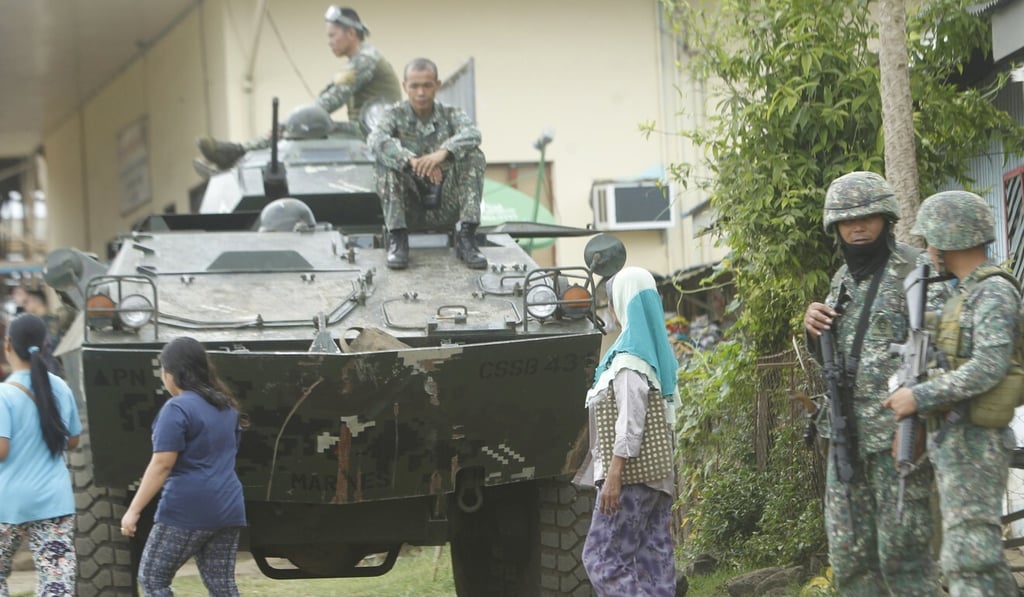Filipinos walk past a tank during military operations in Jolo, Sulu province, in 2017. Photo: EPA