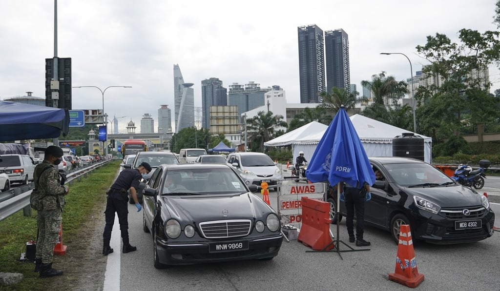 Police check vehicles at a roadblock on the outskirts of Kuala Lumpur on Tuesday after a new movement control order was announced. Photo: AP Police check vehicles at a roadblock on the outskirts of Kuala Lumpur on Tuesday after a new movement control order was announced. Photo: AP