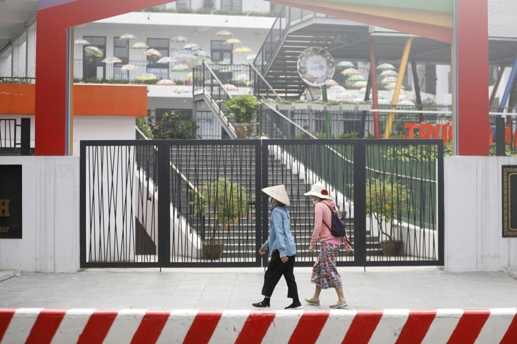 Two women walk past a school in Hanoi, Vietnam, that has been closed due to a rise in Covid-19 cases, on May 4. Developing Asian countries have struggled to meet the sustainable development goals and the largest financing gaps. Photo: EPA-EFE