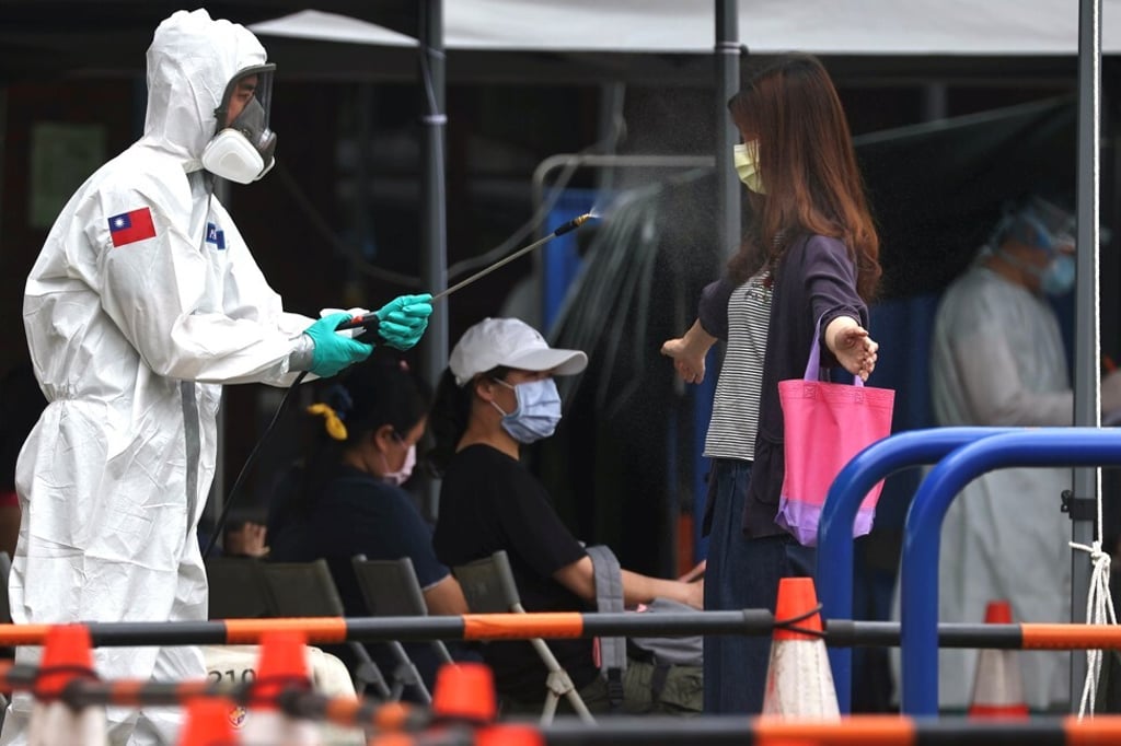 A soldier disinfects a person who is leaving a Covid-19 testing site following a surge of infections in Taipei, Taiwan, May 19, 2021. Photo: Reuters