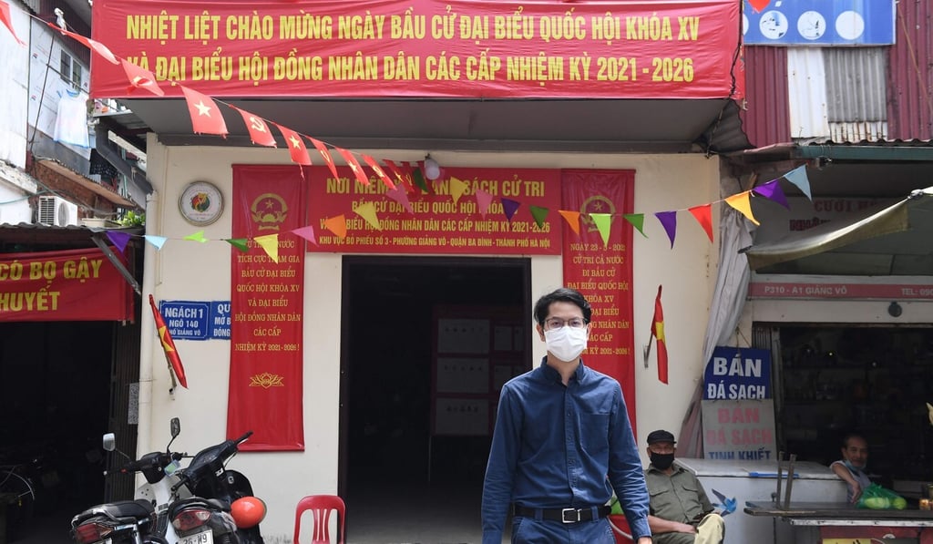 Luong The Huy walks in front of a polling station displaying information about National Assembly candidates in Hanoi. Photo: AFP