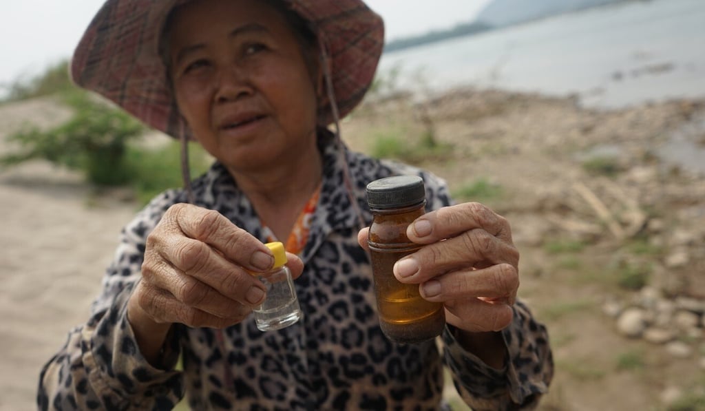 Rodjana Thepwong with jars containing tiny flecks of gold. Photo: Vijitra Duangdee