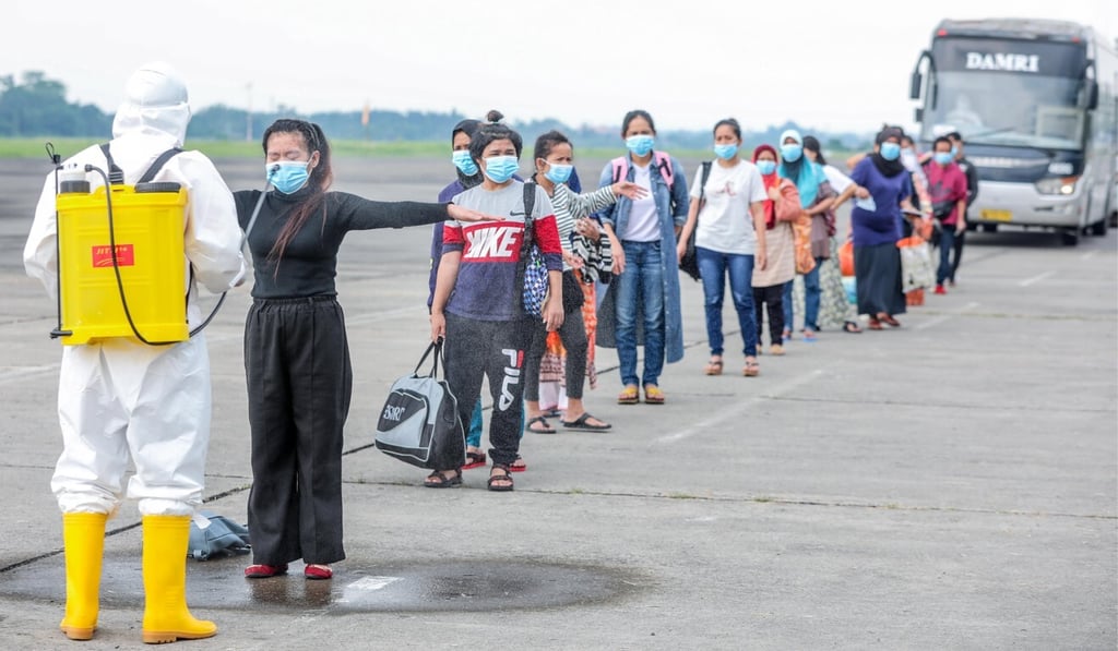 A health worker sprays disinfectant at migrant workers returning from Malaysia. File photo: EPA-EFE