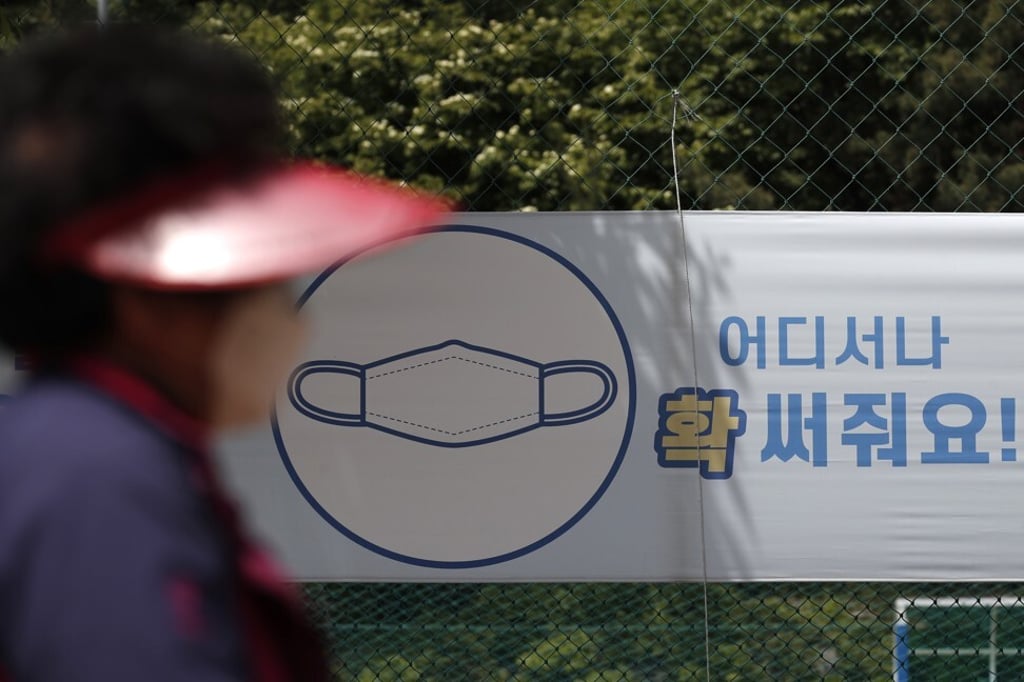 A woman in Seoul walks past a banner bearing Covid-19 advice. Photo: AP