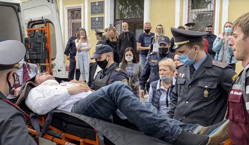 Police and paramedics carry activist Stsiapan Latypau into an ambulance. Photo: Radio Free Europe/Radio Liberty via AP