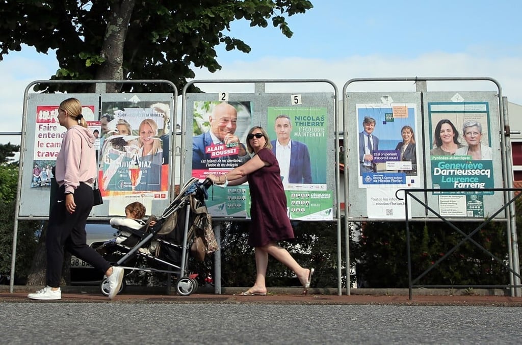 People walk past election campaign posters in Saint Jean de Luz, southwestern France. Photo: AP