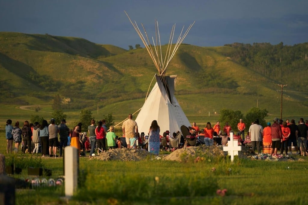 People gather for a vigil in a field where human remains were discovered in unmarked graves at the site of the former Marieval Residential School in Saskatchewan on Friday. Photo: AFP