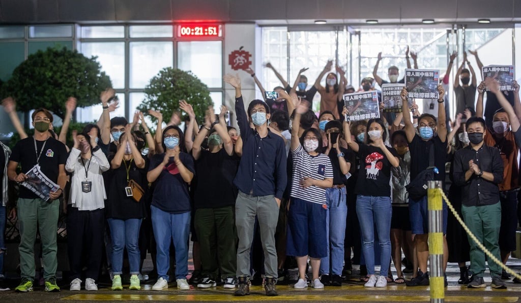 Workers wave outside the headquarters of the Apple Daily newspaper and its publisher Next Digital in Hong Kong, after publishing its last edition. Photo: Bloomberg