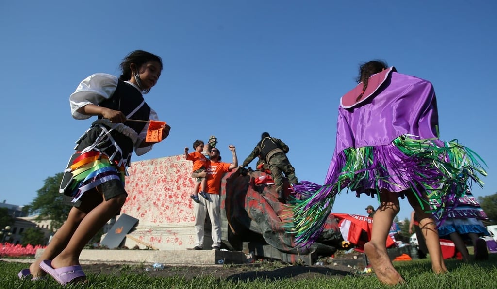 Young dancers circle a statue of Queen Victoria in Winnipeg. Photo: Reuters