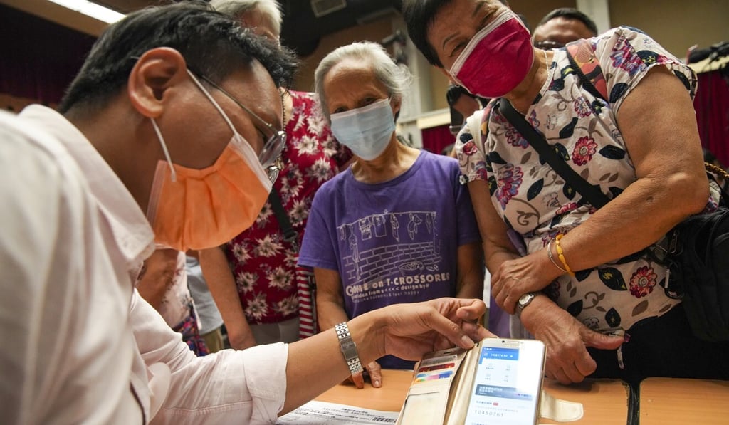 Volunteers help elderly residents register for the voucher scheme at a community centre on Saturday. Photo: Winson Wong