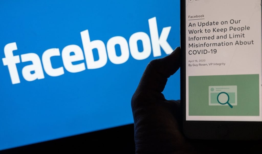 A smartphone screen displays a new policy on Covid-19 misinformation with a Facebook website in the background. Photo: AFP