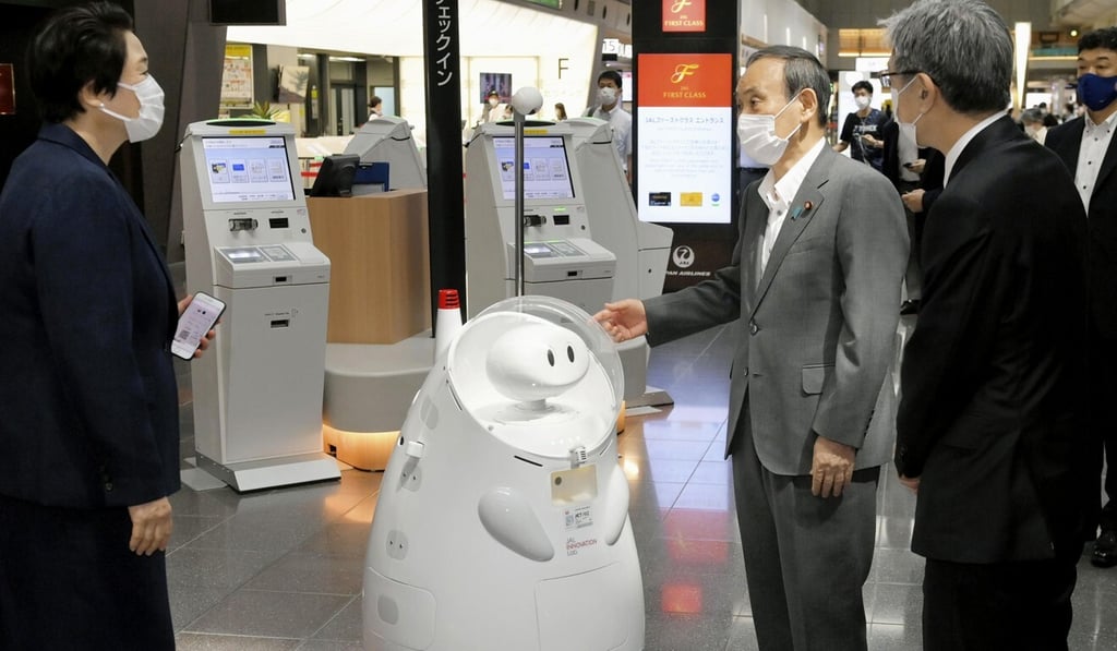 Japanese Prime Minister Yoshihide Suga (centre) stands by a remote-controlled guide robot at Haneda international airport in Tokyo. Photo: Kyodo Japanese Prime Minister Yoshihide Suga (centre) stands by a remote-controlled guide robot at Haneda international airport in Tokyo. Photo: Kyodo