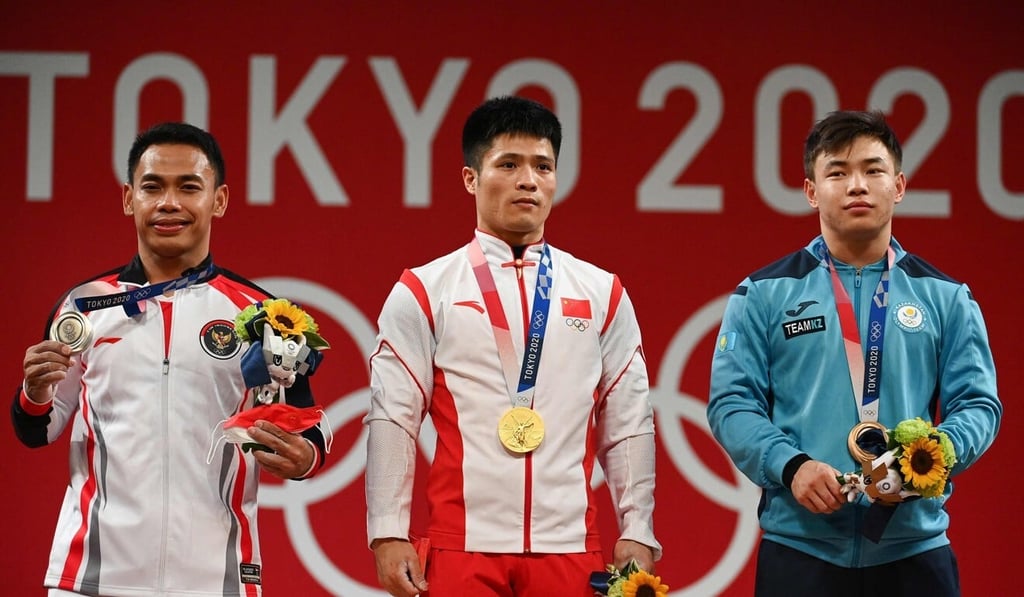 Olympic gold medallist Li Fabin of China (centre) with Indonesian silver medallist Eko Yuli and bronze winner Igor Son, of Kazakhstan at the Tokyo International Forum. Photo: AFP