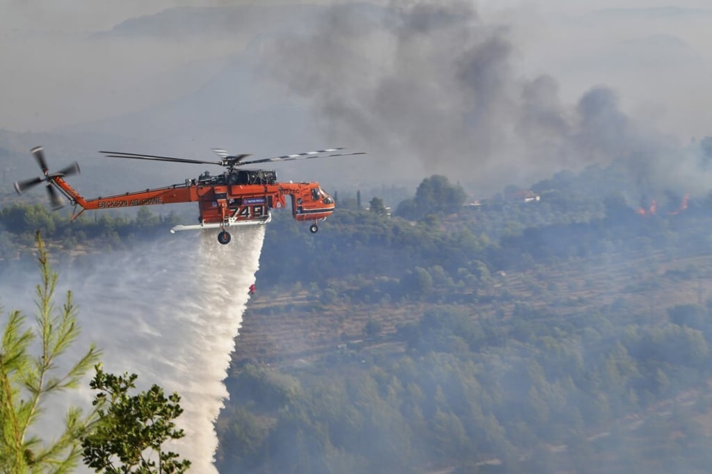 An helicopter drops water during a wildfire in ancient Olympia, western Greece. Photo: ilialive.gr via AP