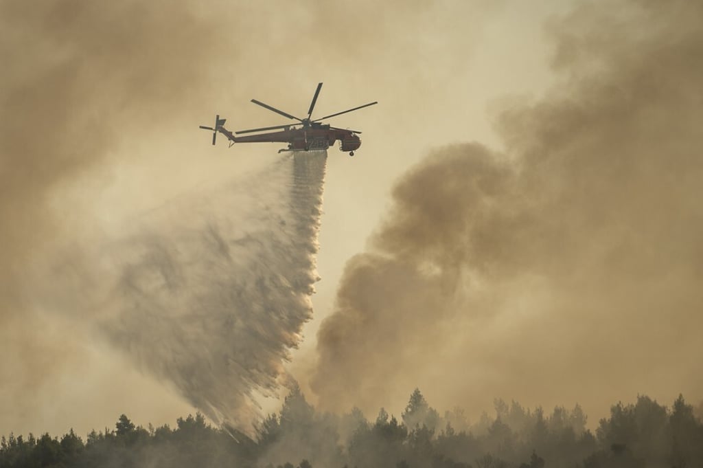 A plane drops water on a fire that broke out in a forest in northern Athens. A plane drops water on a fire that broke out in a forest in northern Athens.