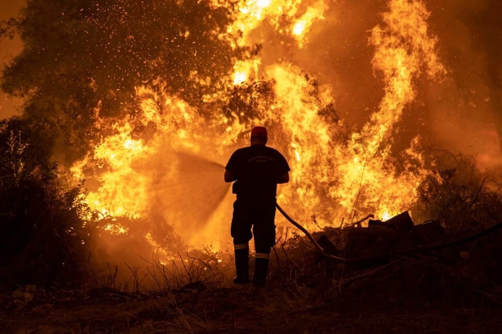 A firefighter tries to extinguish a fire burning in the village of Pefki on the island of Evia, Greece on Sunday. Photo: Reuters A firefighter tries to extinguish a fire burning in the village of Pefki on the island of Evia, Greece on Sunday. Photo: Reuters
