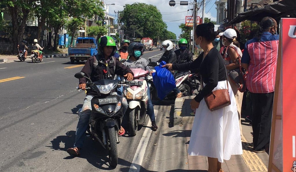 Passers-by in downtown Denpasar pick up food parcels. Photo: Luh Manis Passers-by in downtown Denpasar pick up food parcels. Photo: Luh Manis